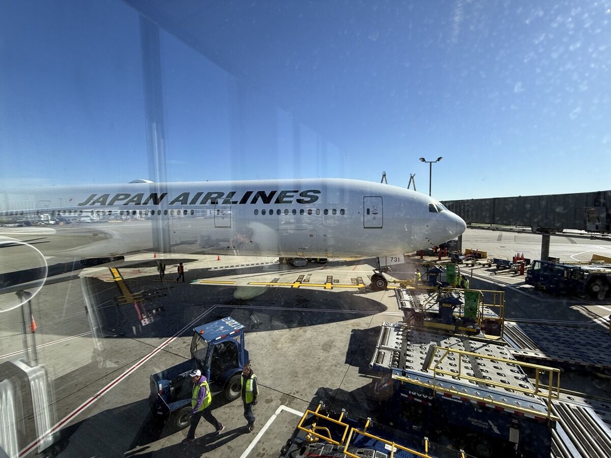 Side view of a Japan Airlines Boeing-787 with ground crew nearby.
