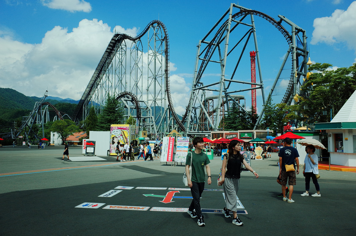 Wide view of Eejanaika, a rollercoaster at Fuji-Q Highland, with two people walking in foreground