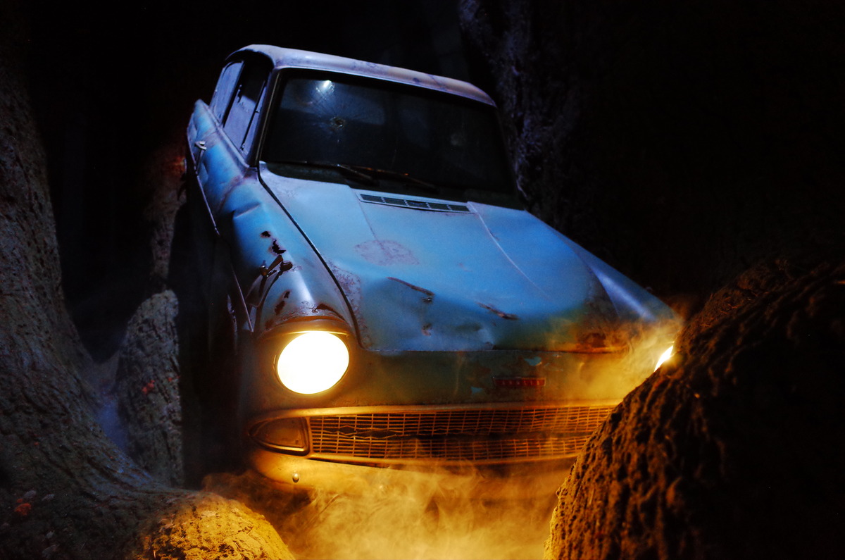 A dented 1960 Ford Anglia 105E in a replica of the Haunted Forest.