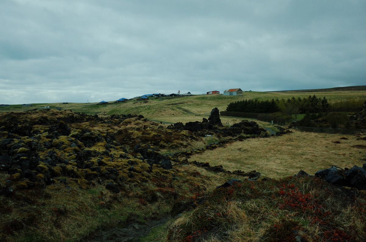 The small village of Hellnar, surrounded by lush green hills.