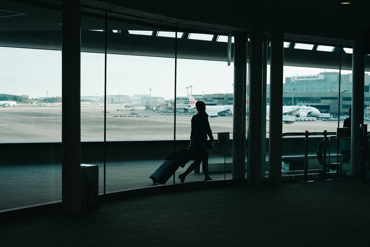 Woman with a rolling suitcase in the Narita airport.