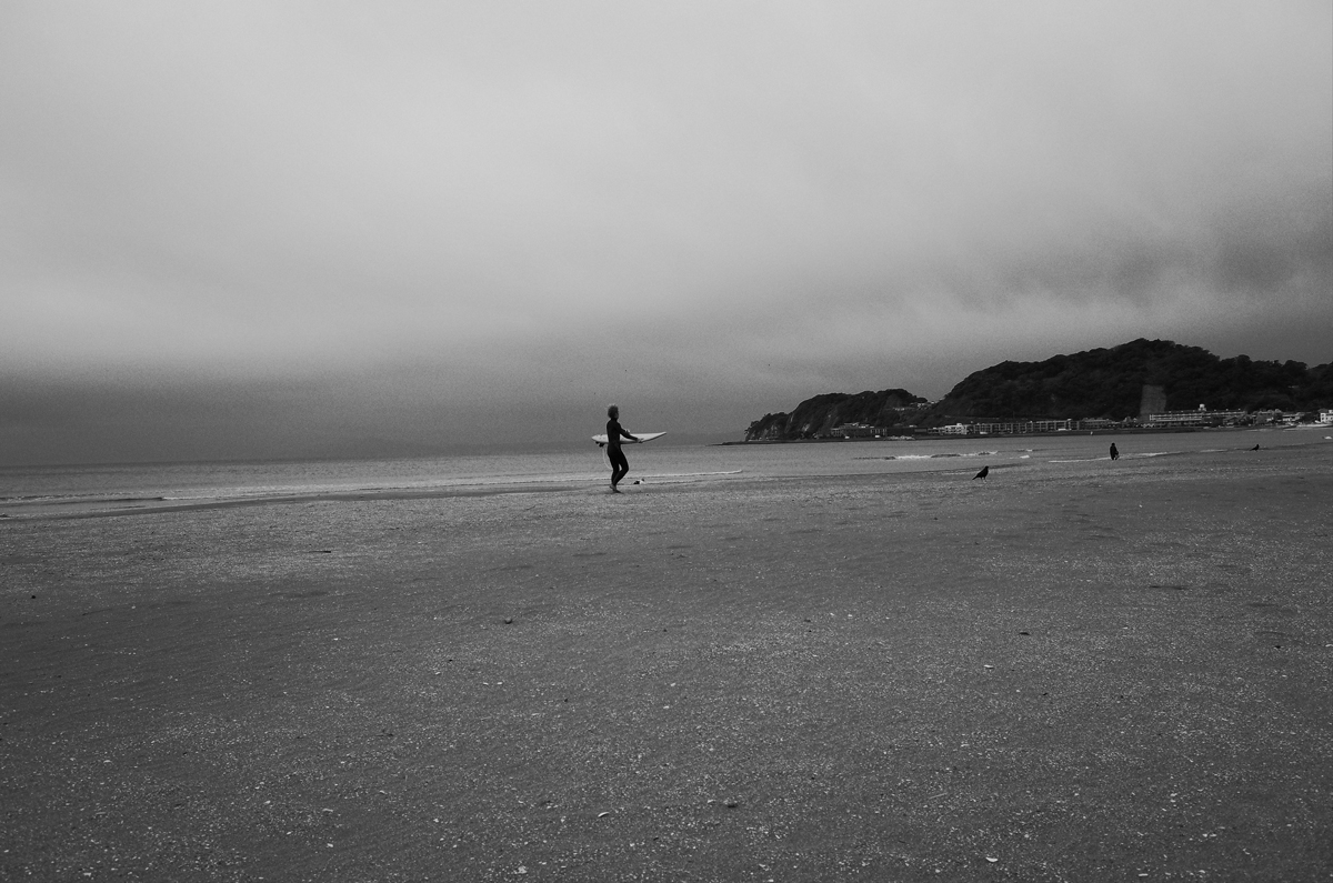 A man with a surfboard on a beach.