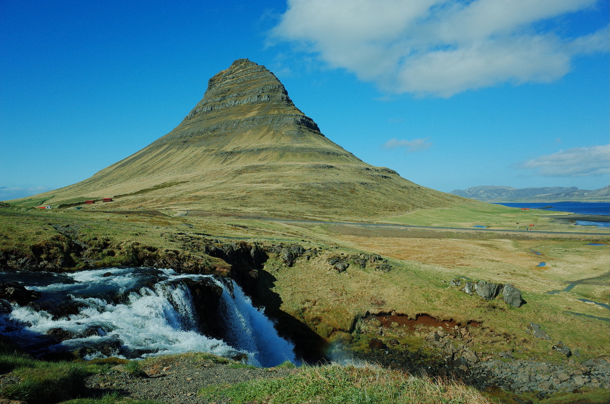 View of Kirkjufell in Iceland, featuring a steep peak with a waterfall cascading in the foreground.