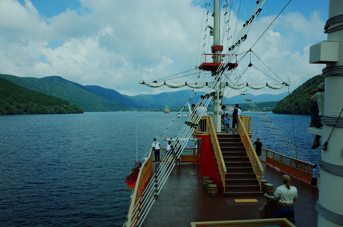 A wooden pirate ship on Lake Ashi with distant hills.
