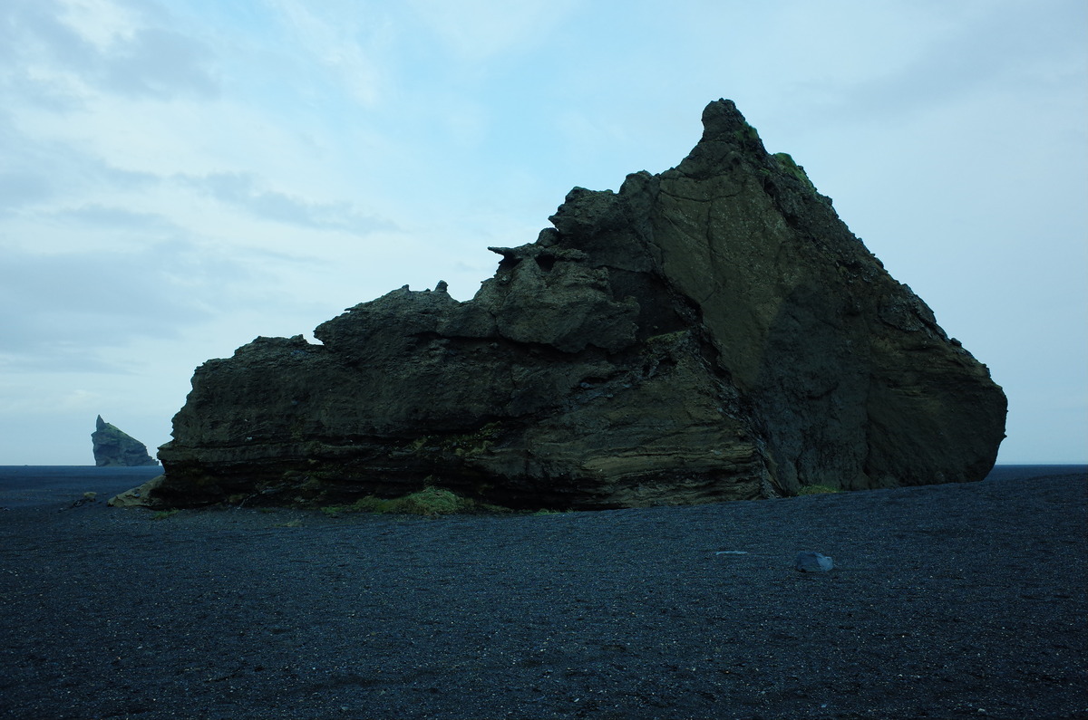 A colossal boulder on an empty plain with a distant boulder in the background.