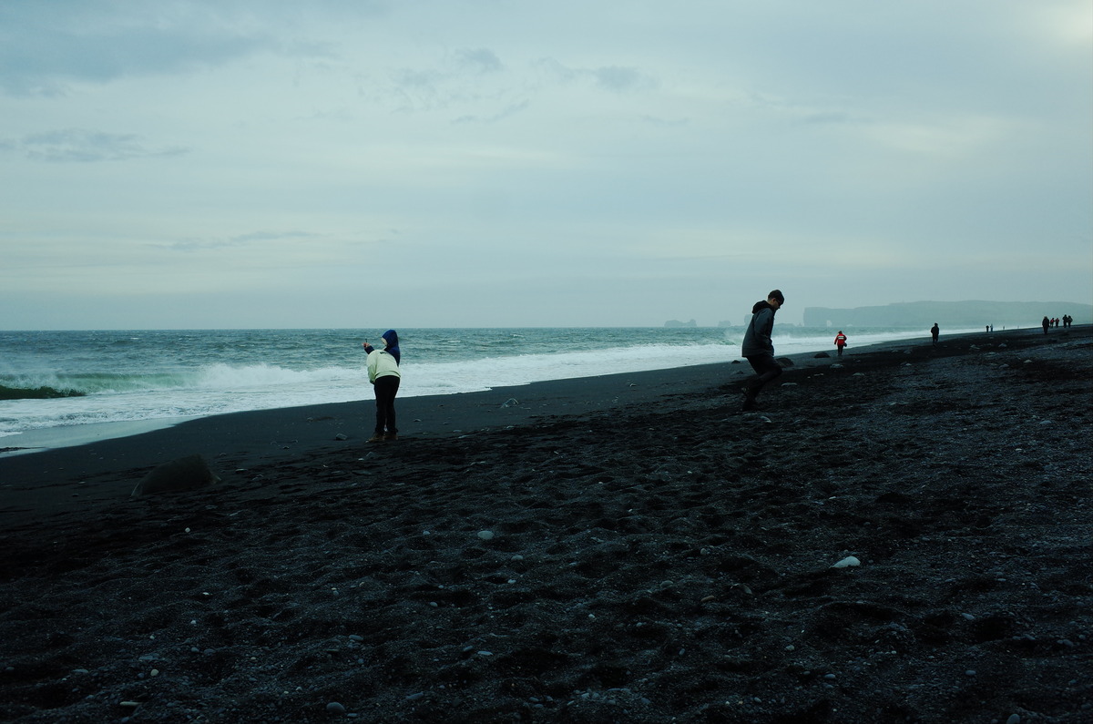 People walking along the black sand beach of Reynisfjara.